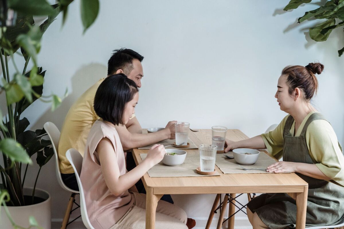 A family enjoys a meal together at home surrounded by indoor plants, capturing a cozy and harmonious moment.