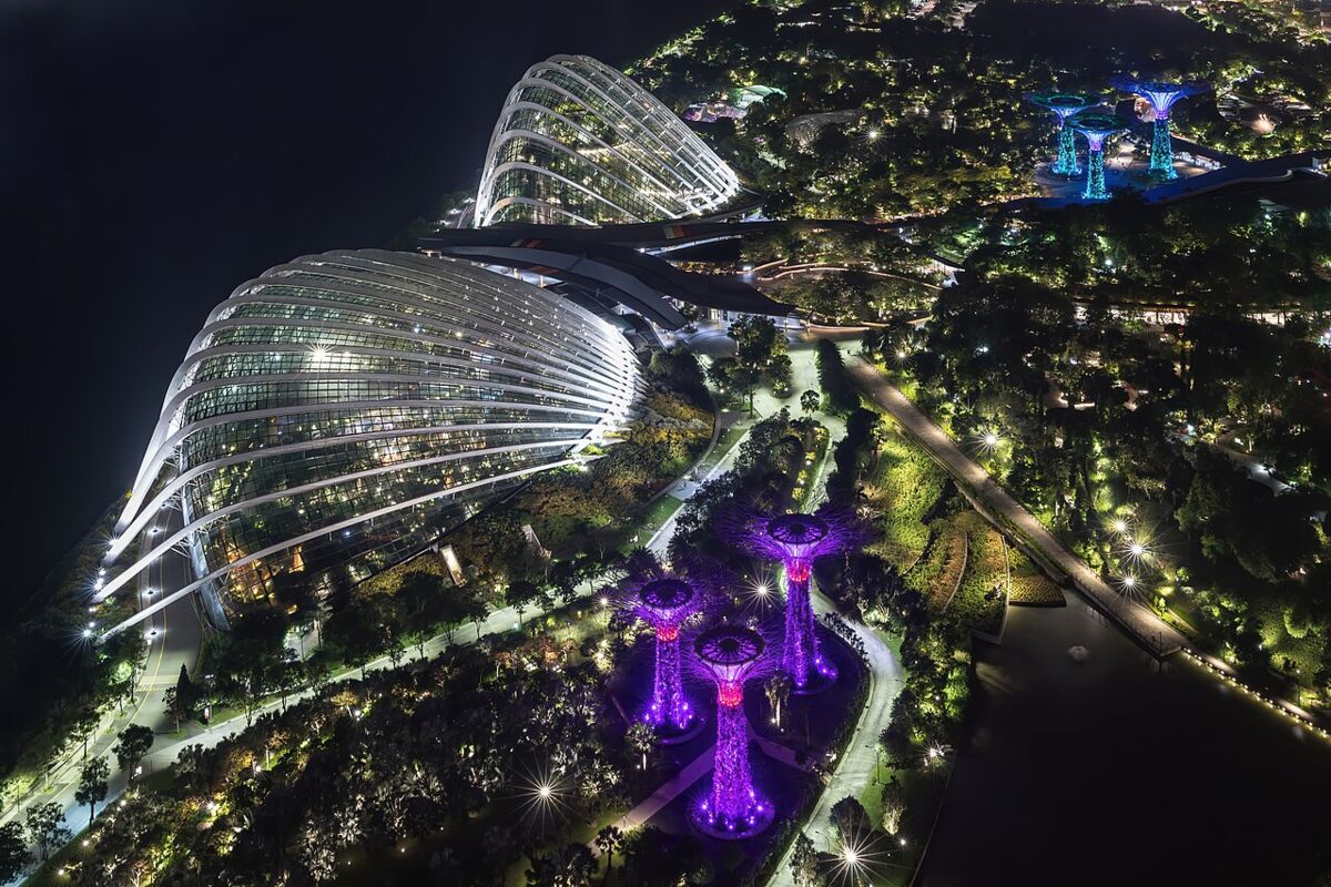 Aerial night view of Gardens by the Bay with the glass conservatory domes and Supertrees glowing purple