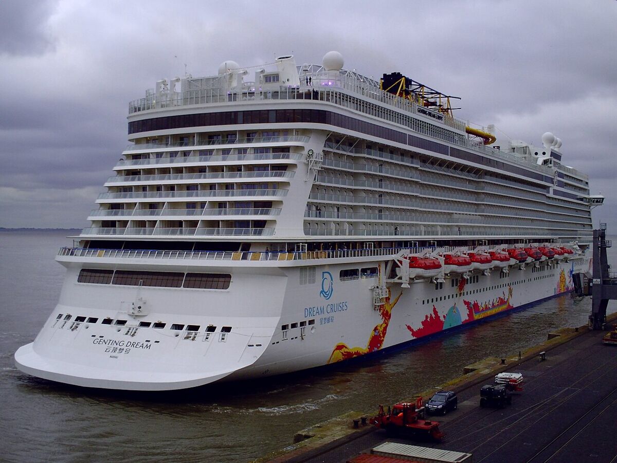 Genting Dream berthed at a cruise terminal, full side view showing decks, lifeboats and Dream Cruises livery