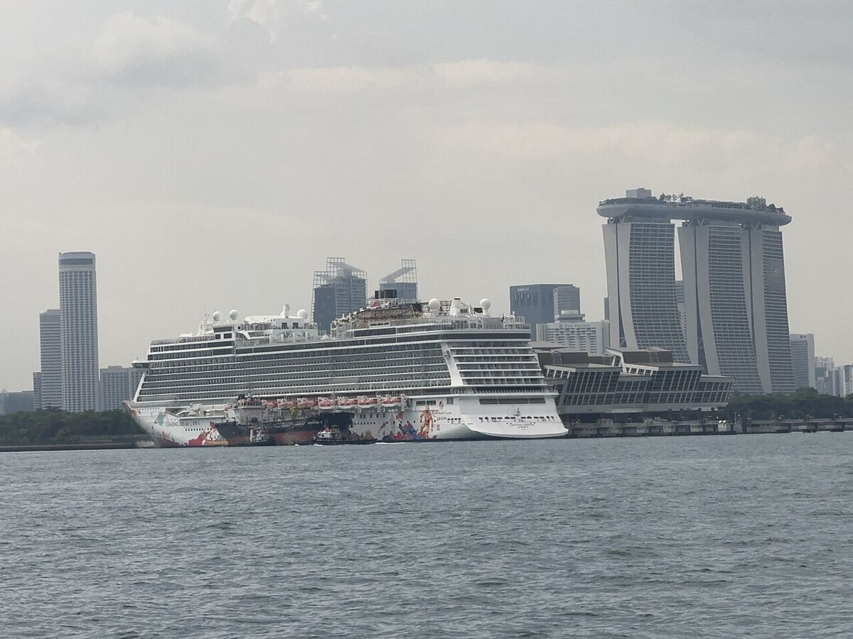 Genting Dream docked at Singapore's Marina Bay with Marina Bay Sands and the city skyline in the background