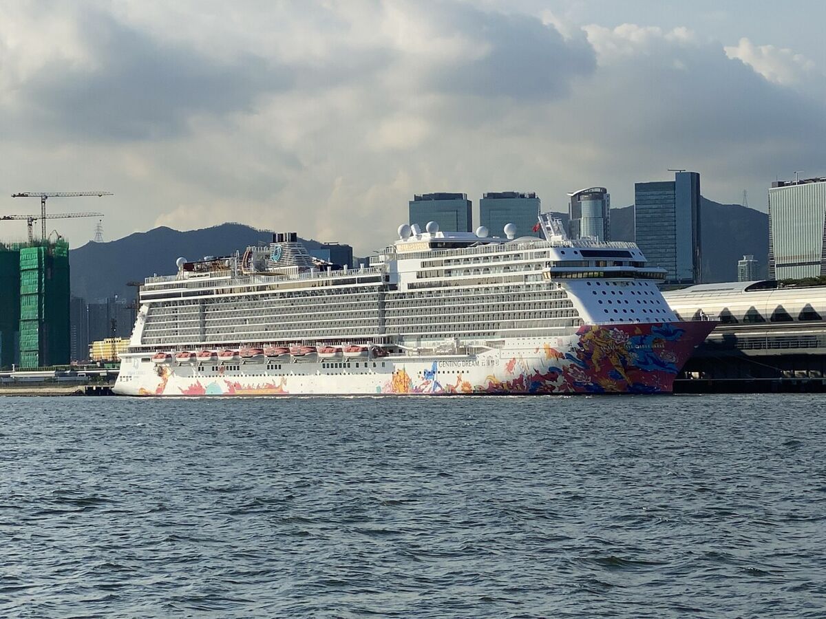 Stern view of Genting Dream at port with a harbour-front city skyline behind the ship