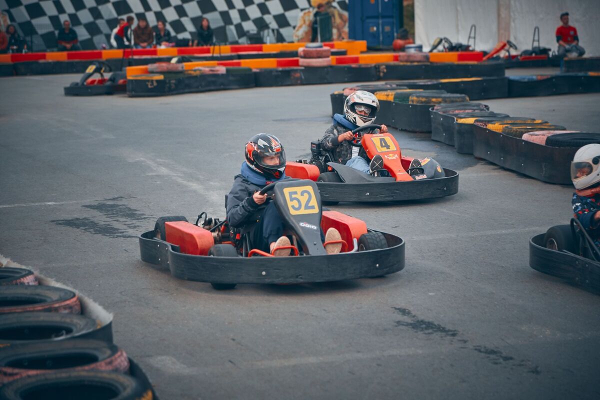 Children in helmets compete in a thrilling go-kart race on an outdoor track.