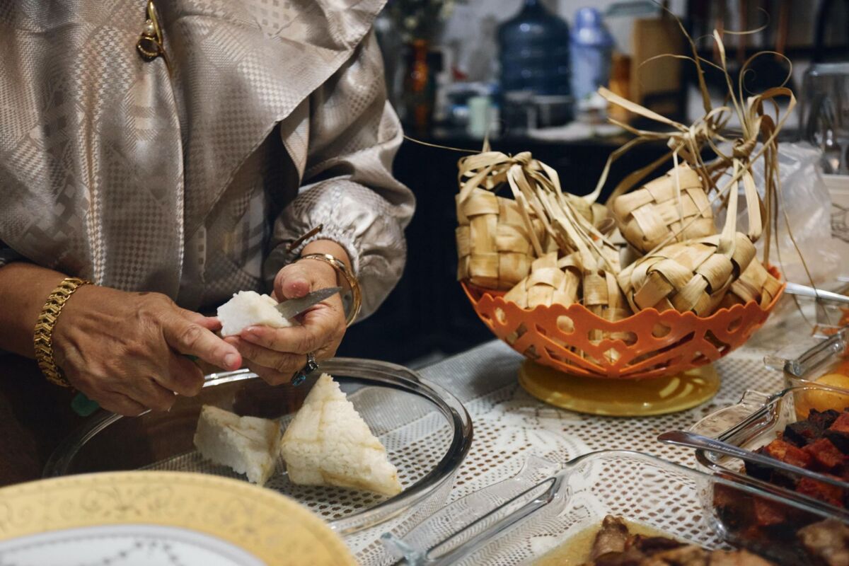 A woman skillfully preparing ketupat, a traditional rice dish, for a festive meal.