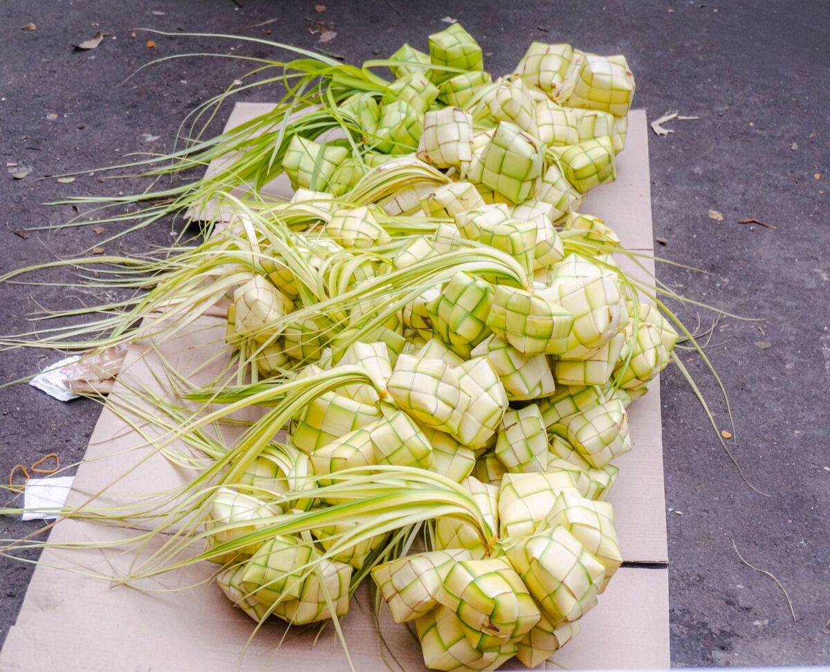 A captivating display of woven ketupat rice packets made from pandan leaves at an outdoor market.