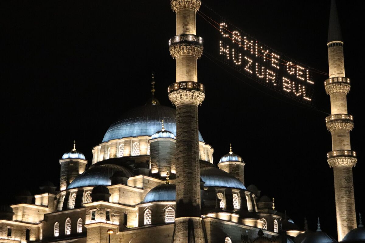 A beautifully lit mosque at night with festive Ramadan lights displaying a welcoming message.