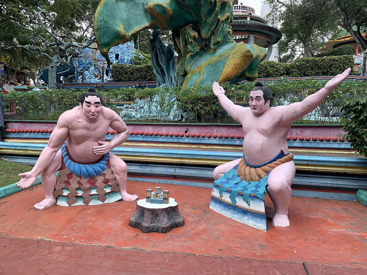 Pair of sumo wrestler statues facing off on a red plaza at Haw Par Villa, Singapore