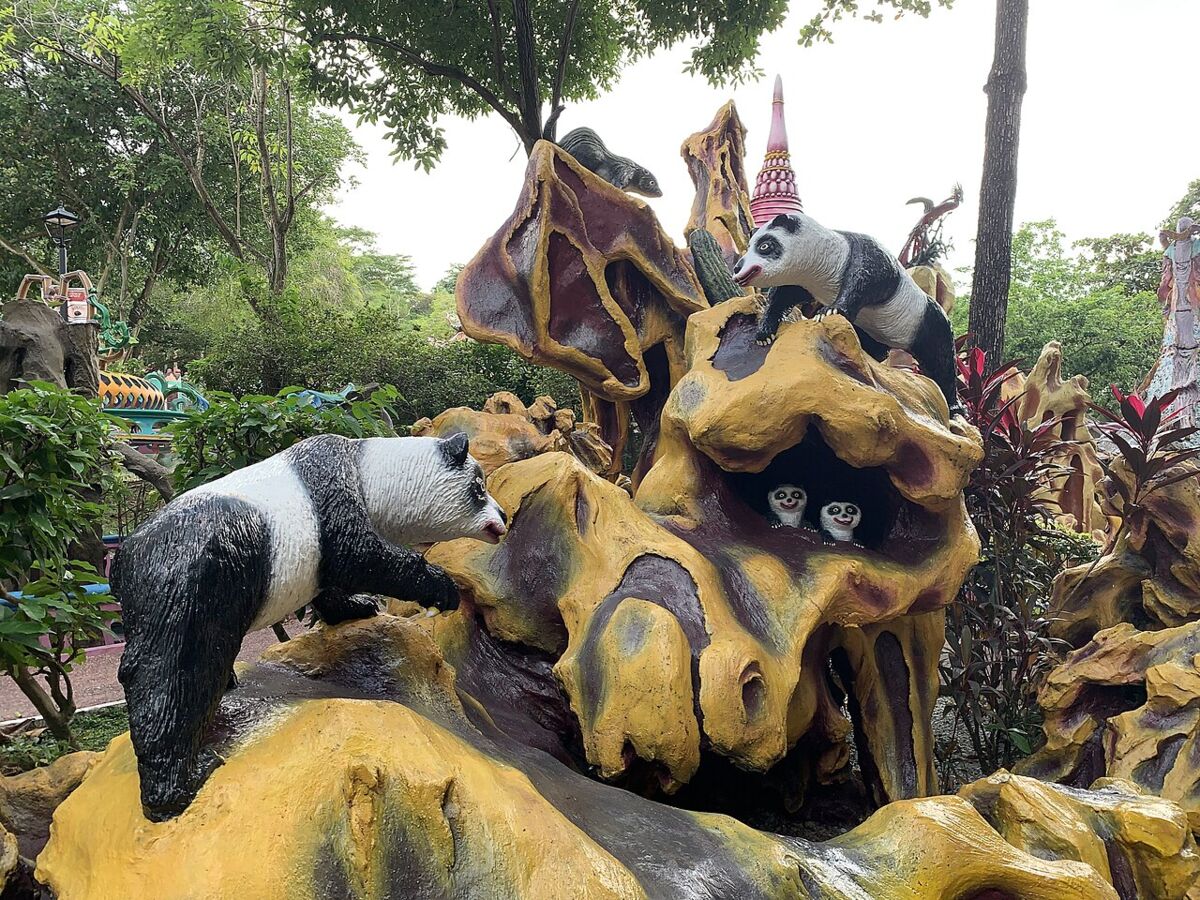 Whimsical panda bear diorama set into yellow rockwork with cub statues at Haw Par Villa
