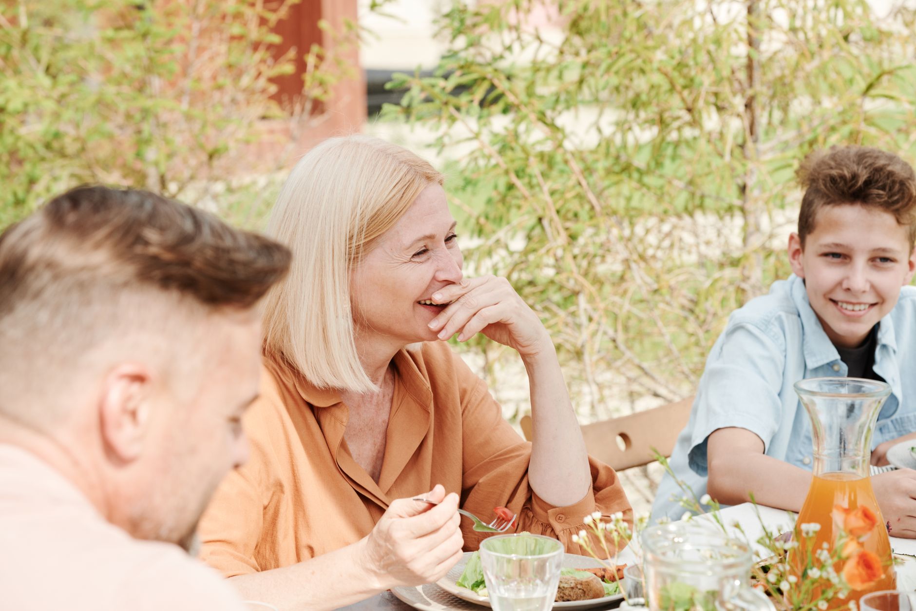 A cheerful family enjoying a meal together in a serene outdoor garden setting.