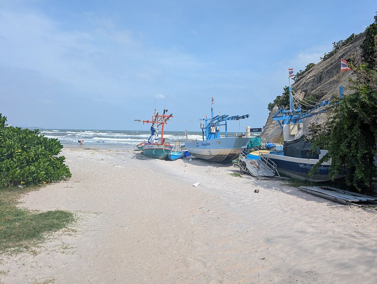 Colourful Thai fishing boats pulled up on the white sand at the rocky northern end of Hua Hin Beach