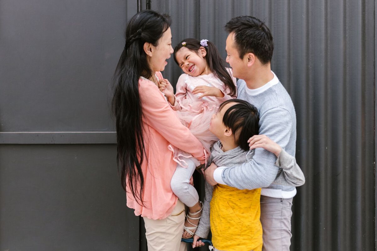 Joyful Asian family sharing a playful moment together in a warm outdoor setting.