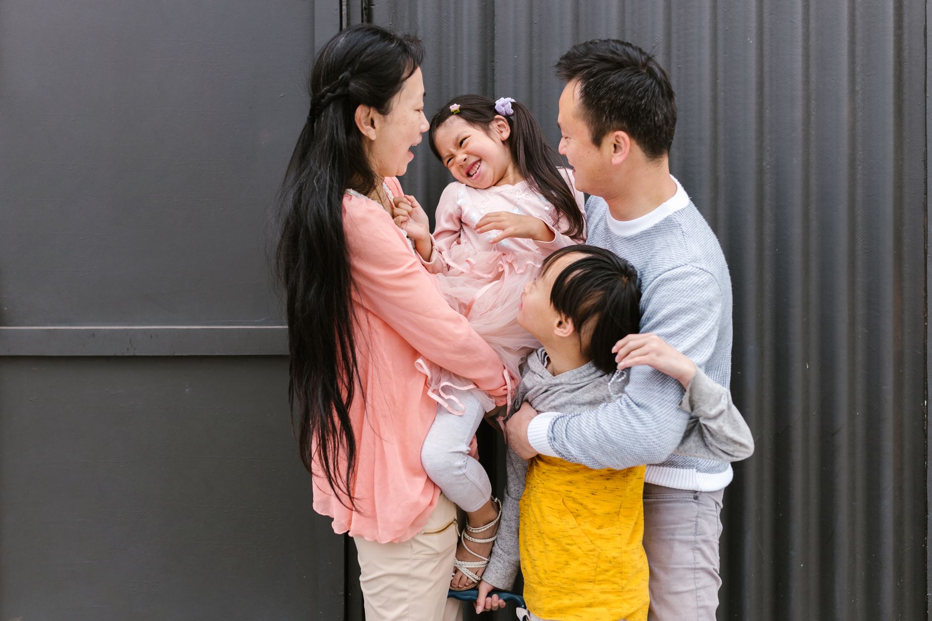 Joyful Asian family sharing a playful moment together in a warm outdoor setting.