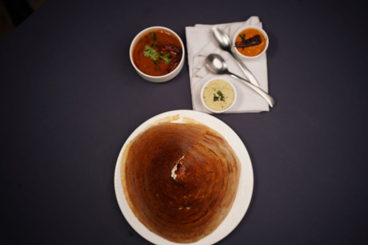 Top view of a traditional South Indian dosa meal with chutneys and sambar.