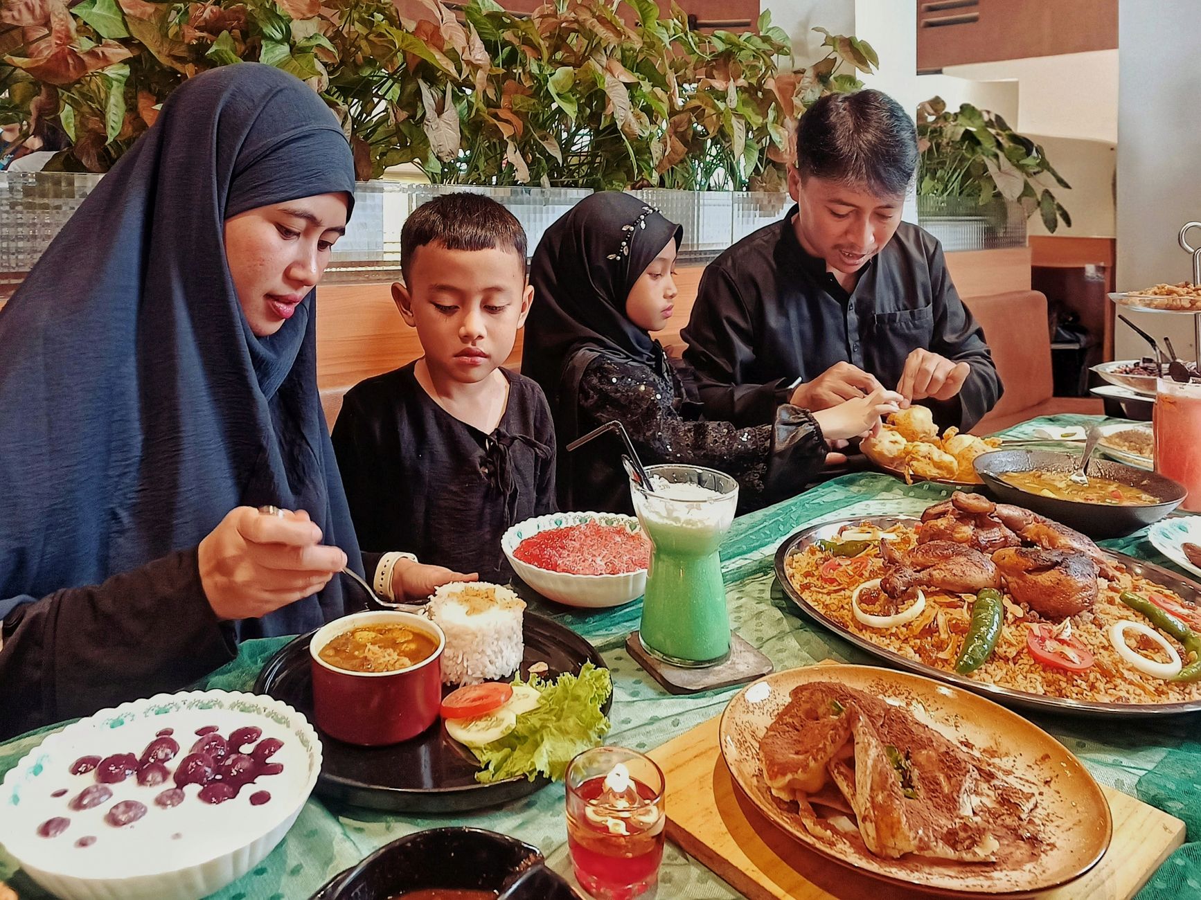 A family enjoys a meal of traditional Indonesian dishes at a restaurant in Jawa Barat.
