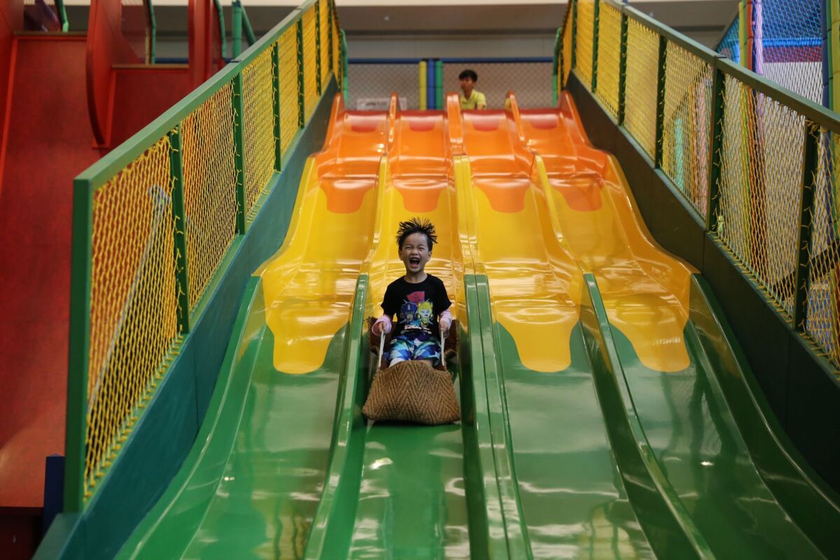 A cheerful child sliding down a colorful slide in an indoor playground, showcasing fun and excitement.