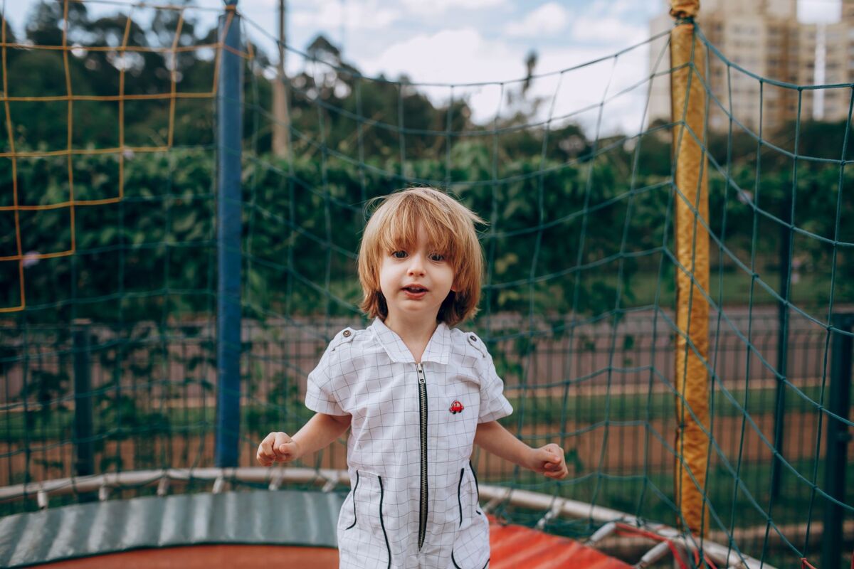 A young child enjoying a fun day on a trampoline in a park setting during summer.