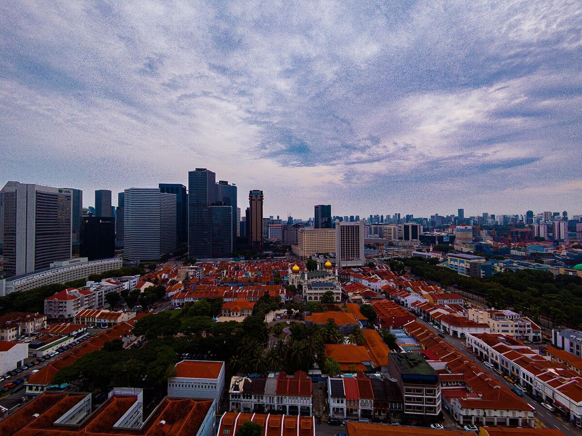 Aerial view of the red-tiled shophouse roofs of Kampong Glam with Sultan Mosque and the city skyline beyond, Singapore