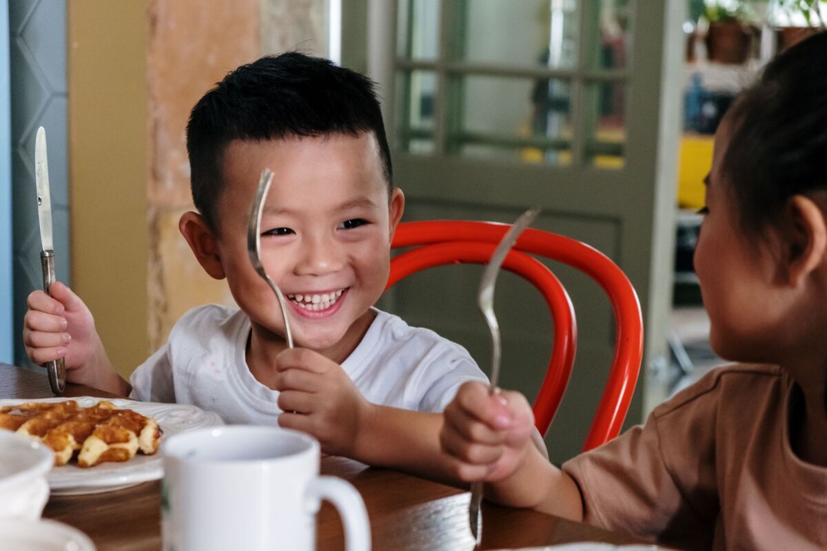 Two smiling children enjoying breakfast together at home with waffles.
