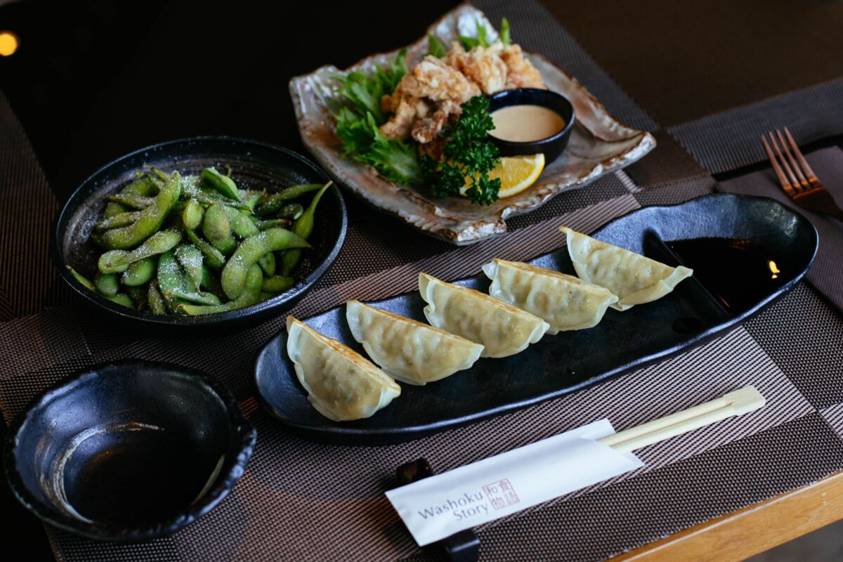 A beautifully arranged Japanese meal featuring gyoza, edamame, and karaage artfully plated.