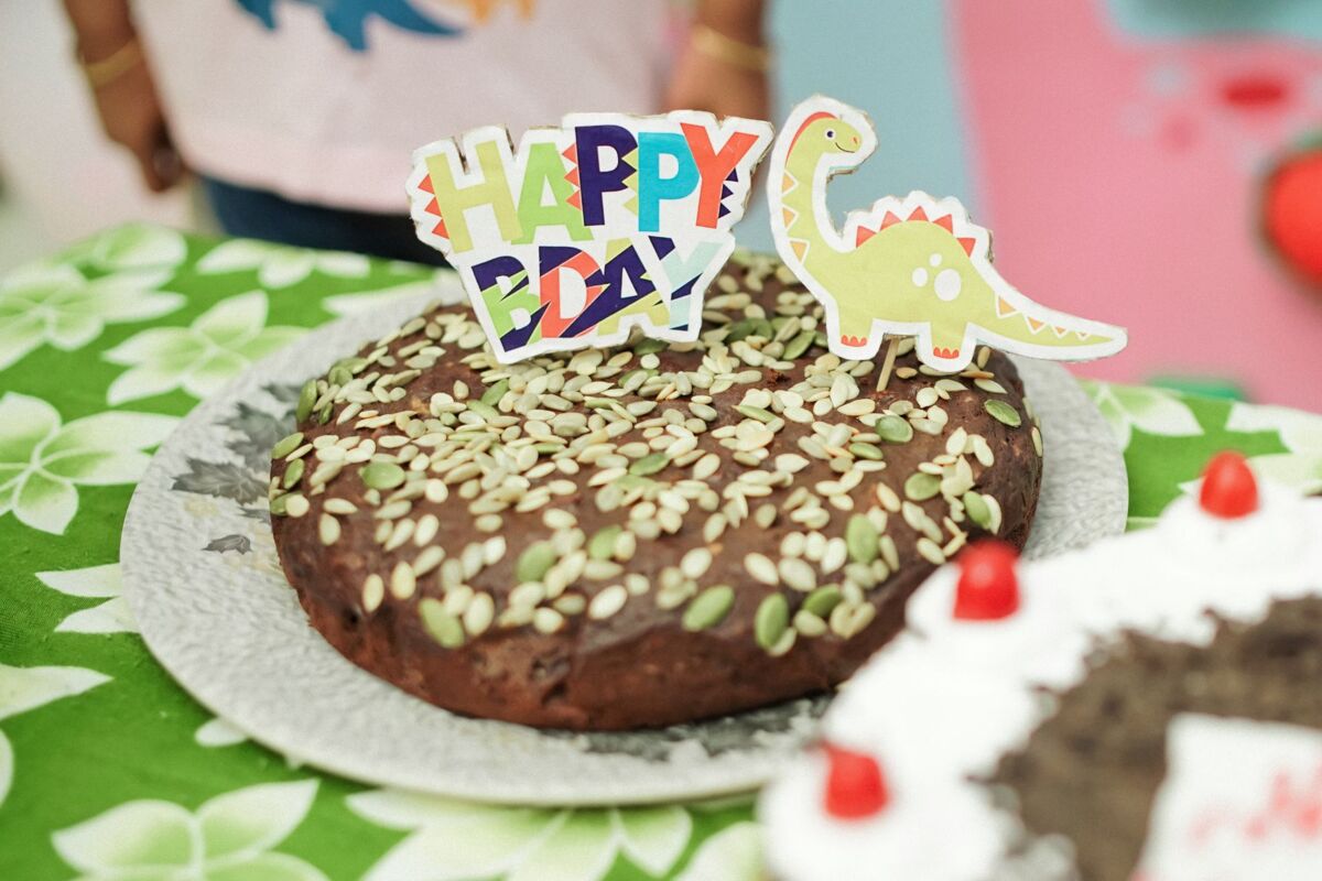 A fun dinosaur-themed birthday cake with colorful decorations and seeds.