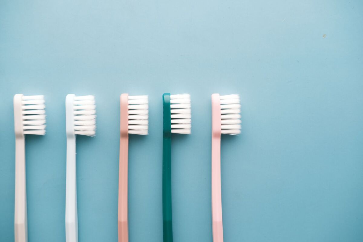 A row of five colorful toothbrushes arranged on a blue background, perfect for dental care themes.