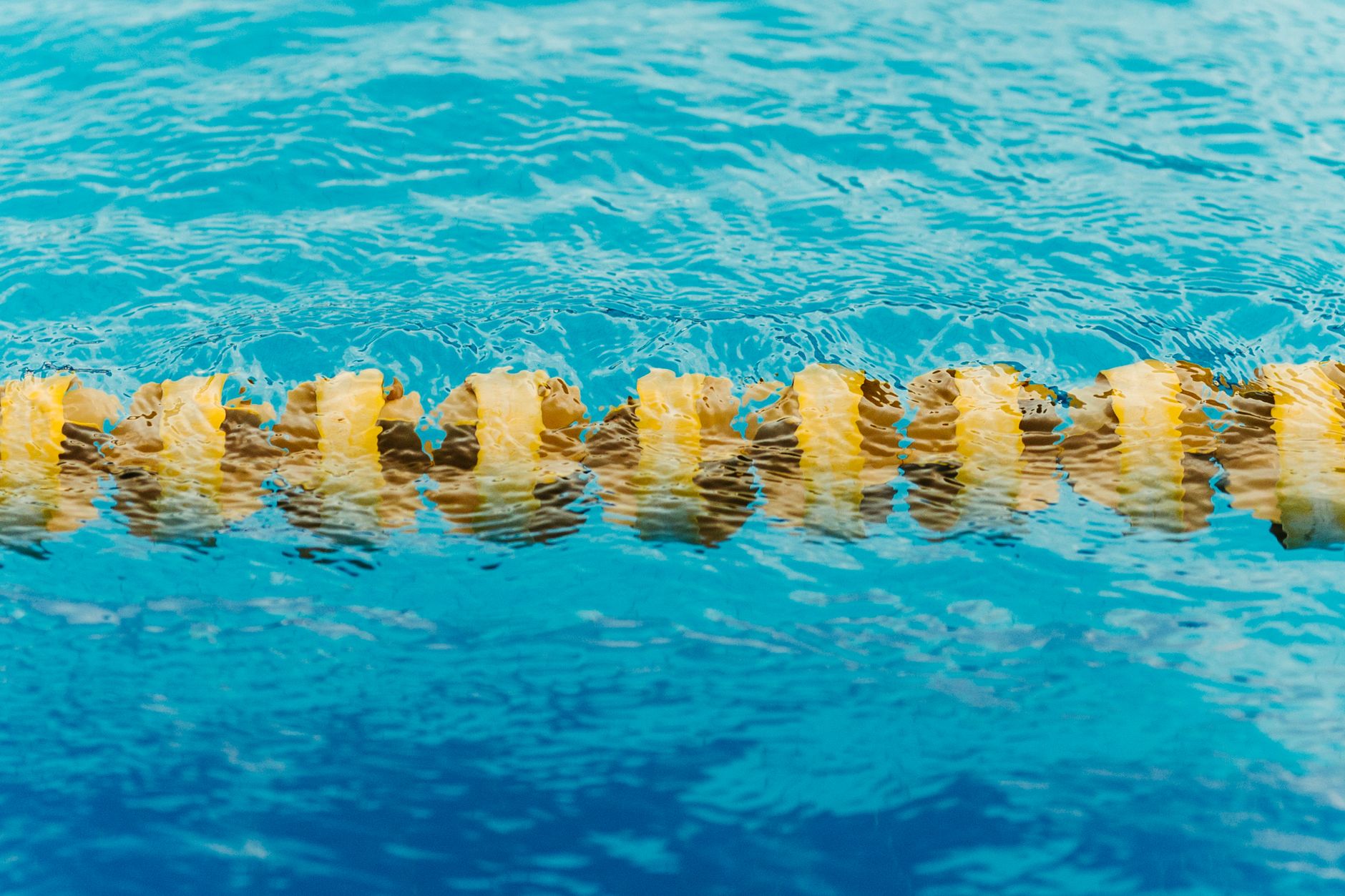 Close-up of yellow lane marker floating in a blue swimming pool, vibrant and refreshing.