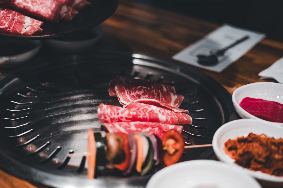 Close-up of Korean BBQ with sliced beef and fresh vegetables on grill.