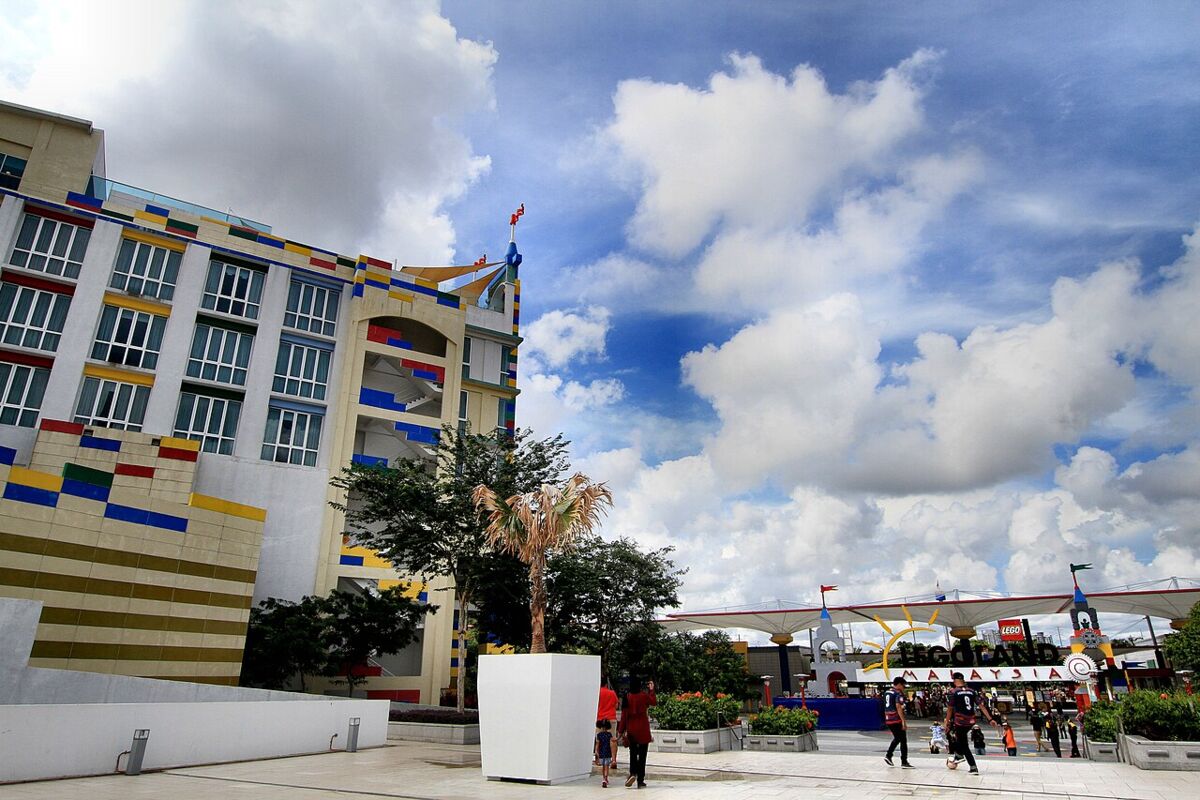 Open plaza at Legoland Malaysia with the colourful Lego-brick building and theme park entrance under a blue cloudy sky