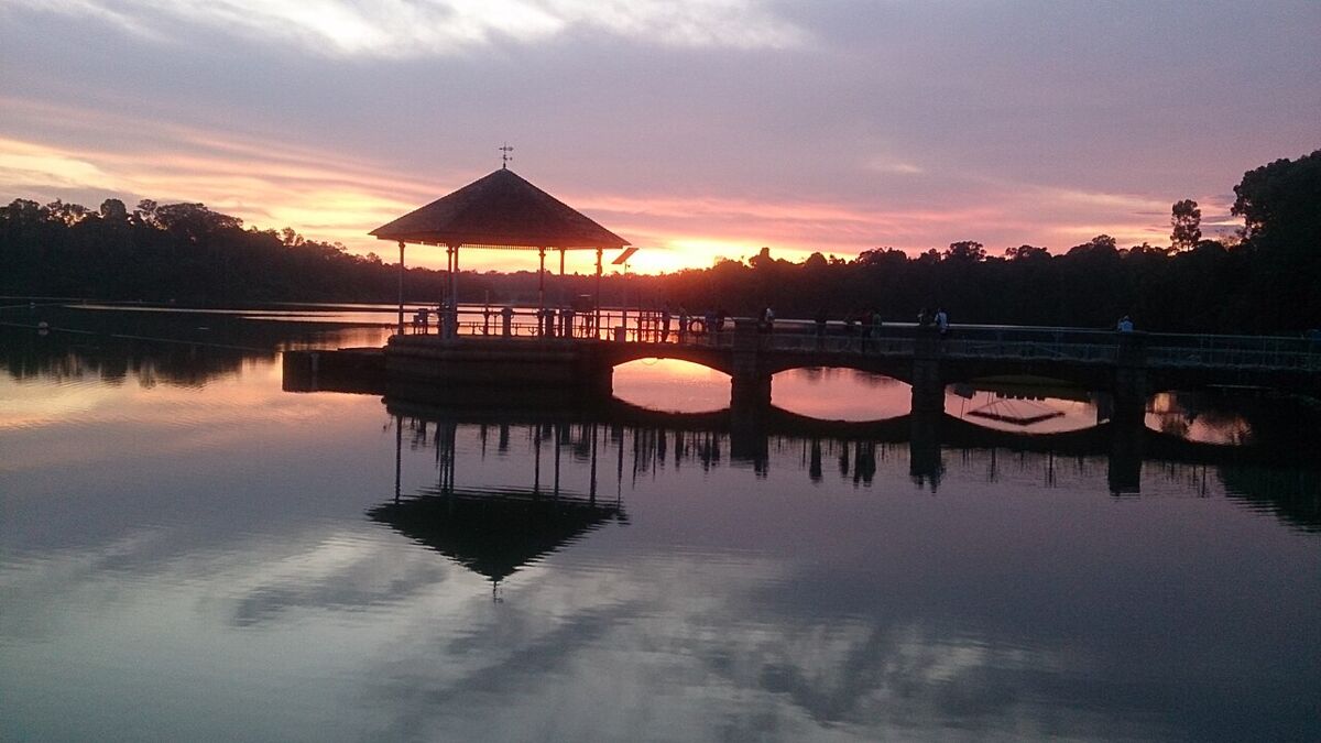 Silhouette of the Lower Peirce Reservoir pavilion and bridge against a pink and orange sunset sky