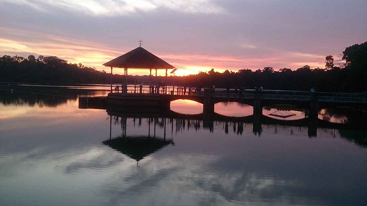 Silhouette of the Lower Peirce Reservoir pavilion and bridge against a pink and orange sunset sky