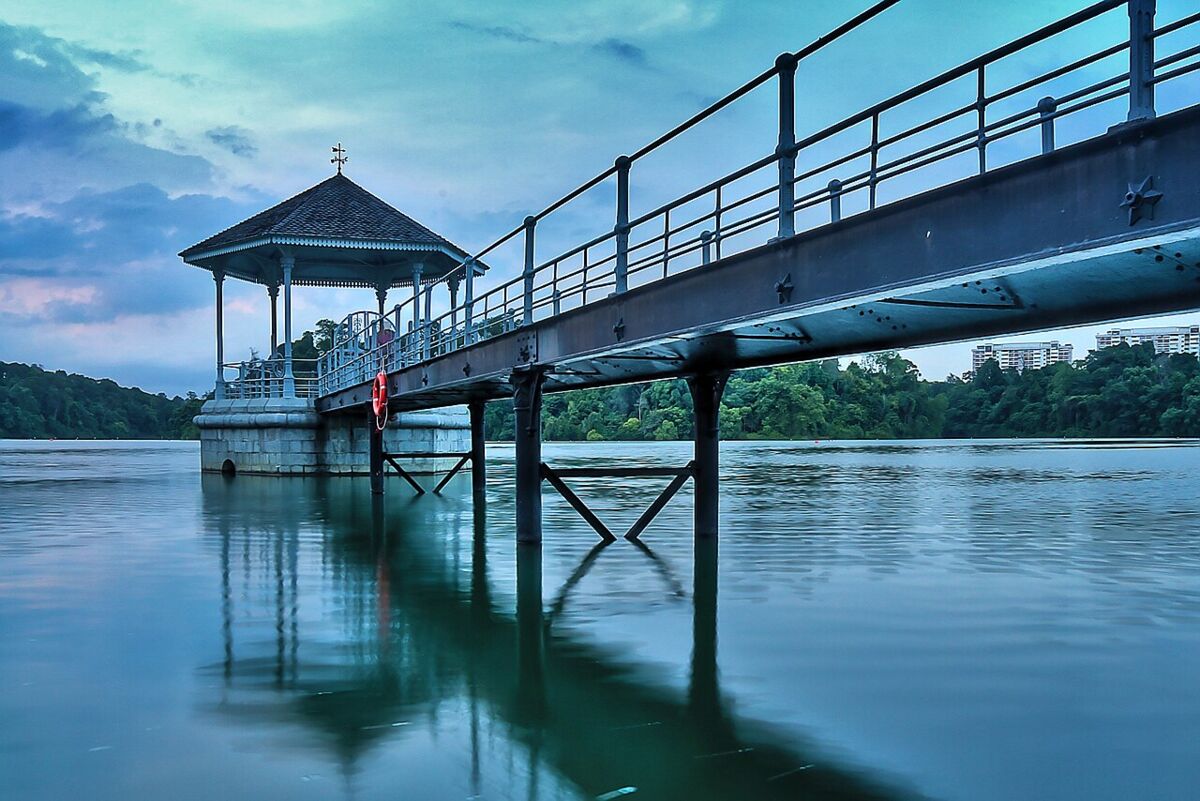 The iconic lakeside pavilion and footbridge at MacRitchie Reservoir reflected in calm water at dusk