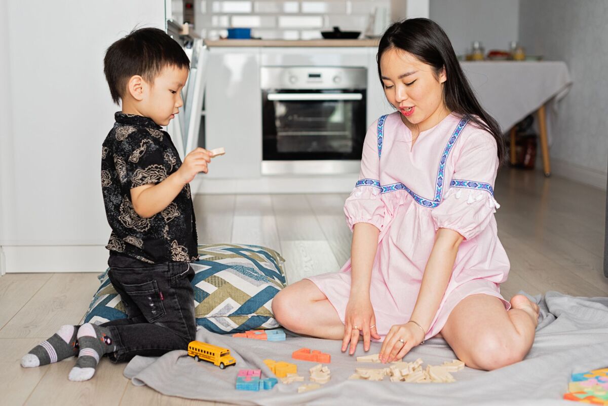 Asian mother and son engaging in a playful learning activity with toys at home.
