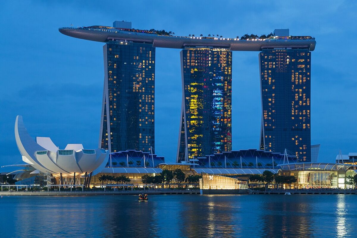 Marina Bay Sands hotel towers lit up at blue hour, with the ArtScience Museum reflected in the water