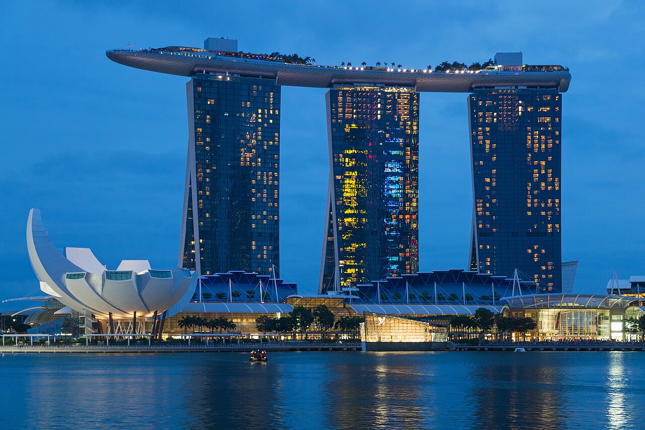 Marina Bay Sands hotel towers lit up at blue hour, with the ArtScience Museum reflected in the water