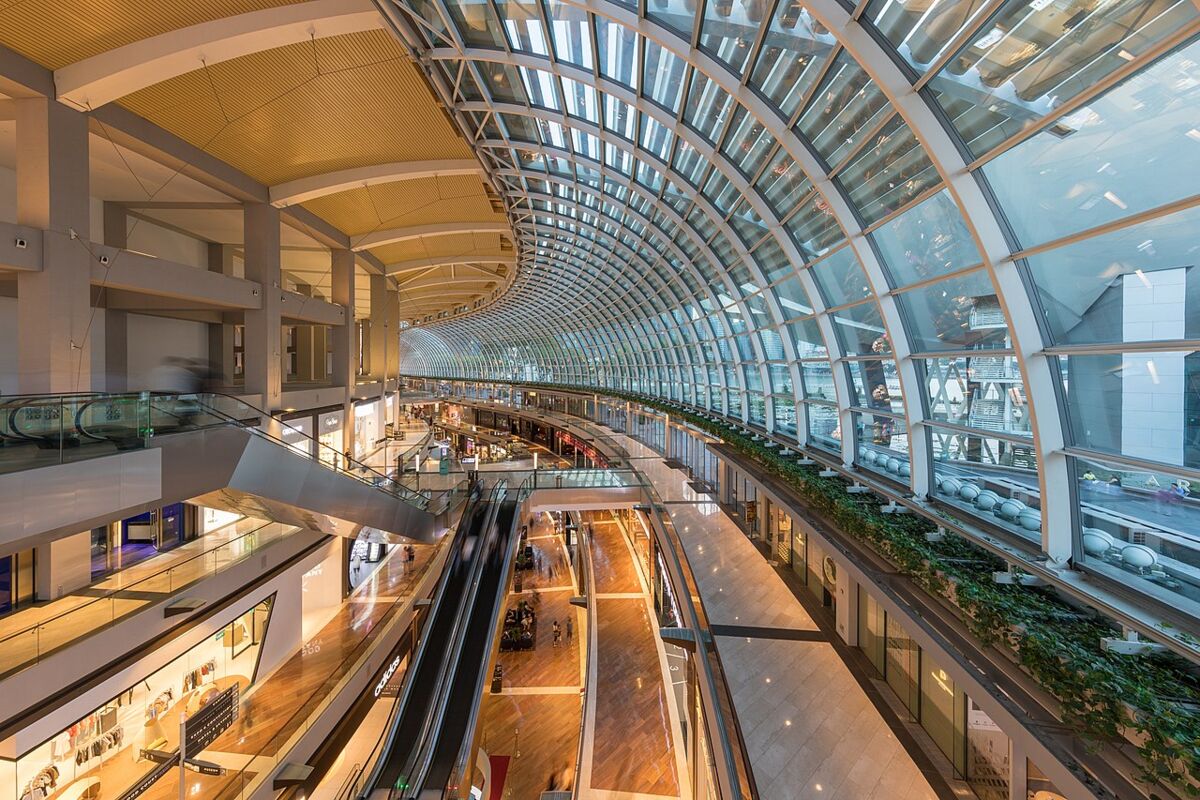 Interior of The Shoppes mall at Marina Bay Sands with curved glass roof and multiple levels of escalators