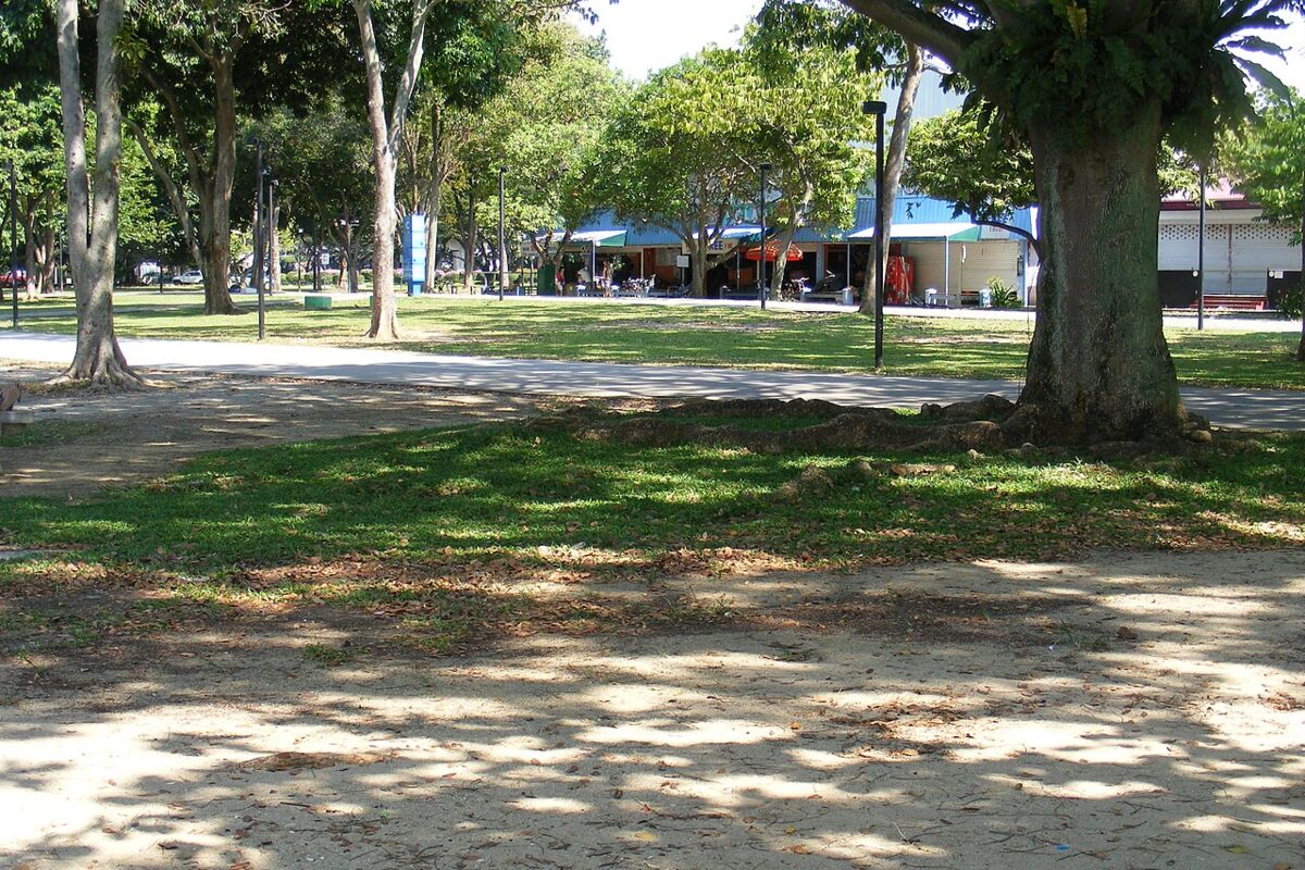 Shaded grassy lawn with mature trees and food kiosks at East Coast Park near Marine Parade