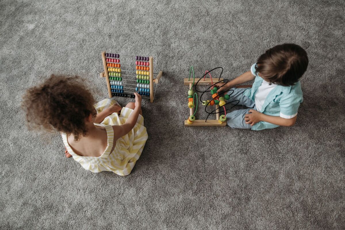 Two children enjoy educational play with a colorful abacus and wooden toy.