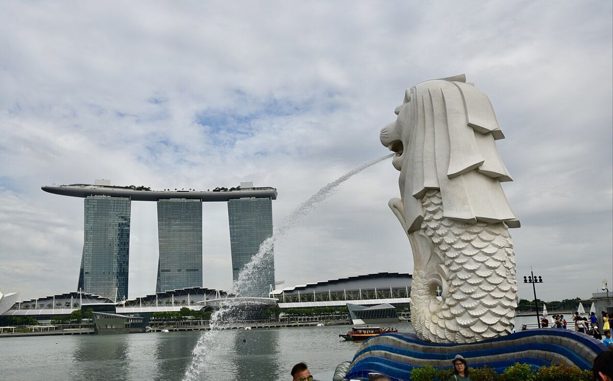 Side view of the Merlion statue spouting water across Marina Bay with Marina Bay Sands in the background