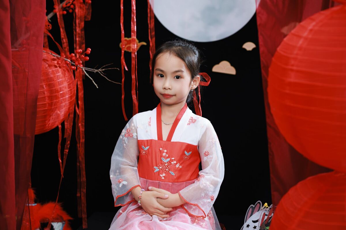 Portrait of a young girl in traditional attire celebrating Mid-Autumn Festival with lanterns and festive decor.
