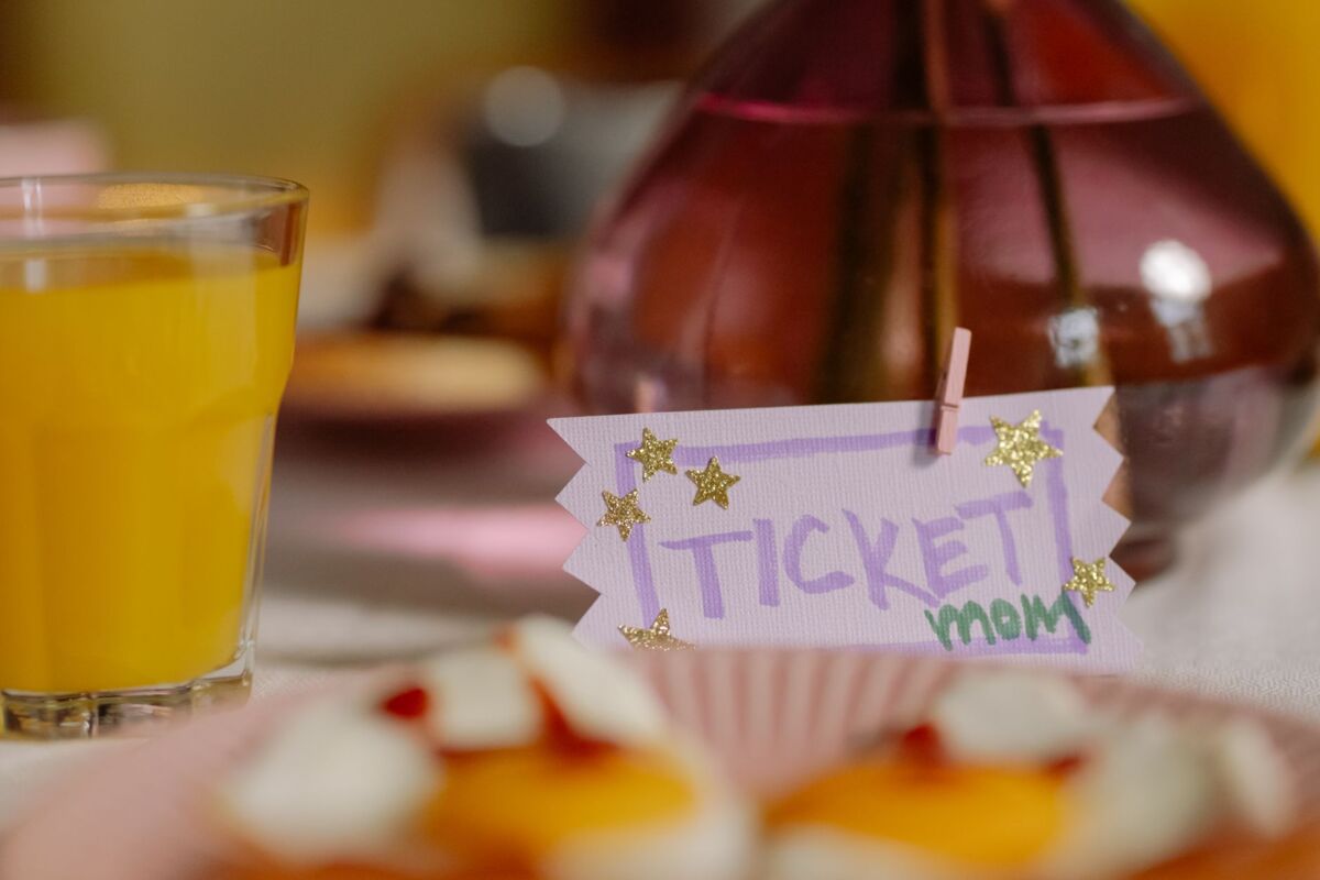 A close-up of a vibrant table setting with a glass of orange juice and a decorative greeting card.