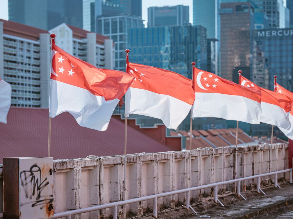 Singapore national flags waving in front of a modern urban skyline, signifying national pride and city life.