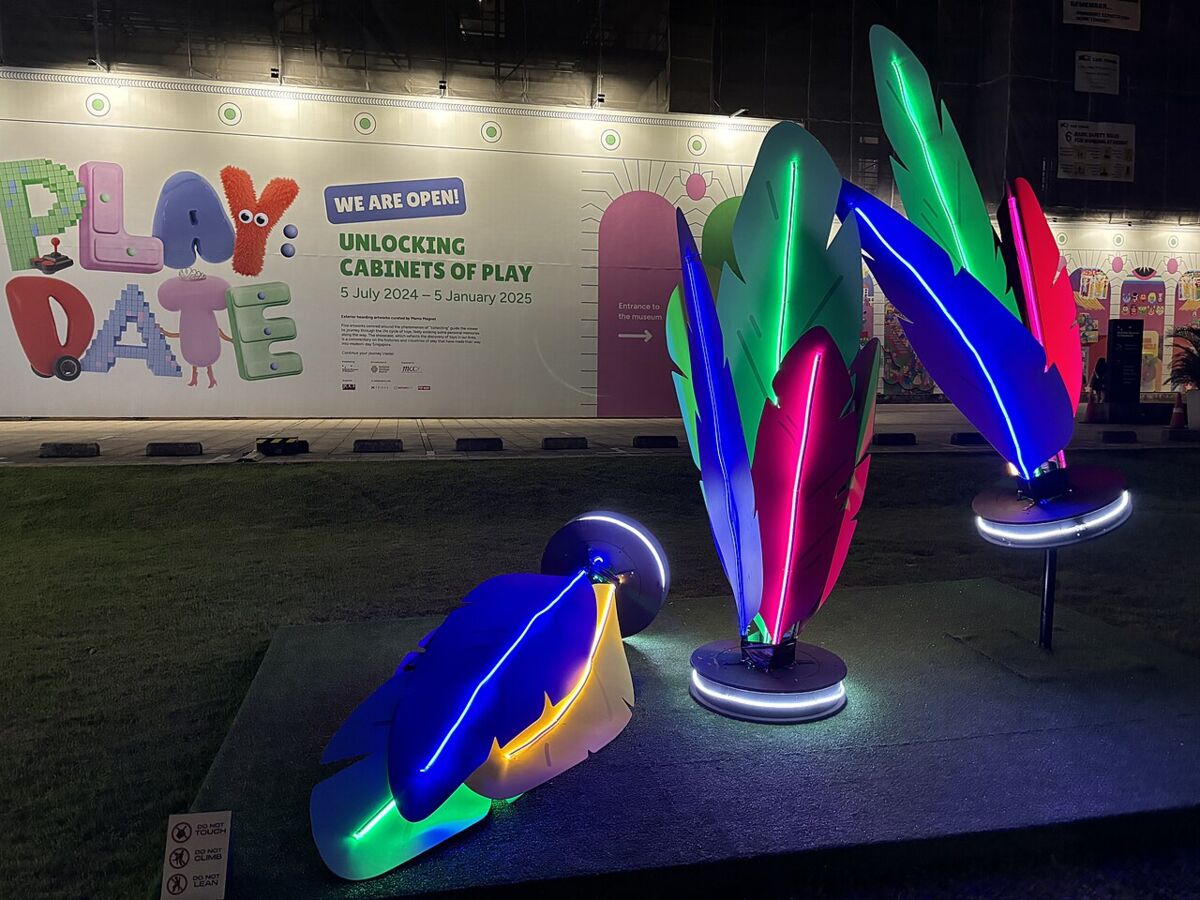Colourful illuminated feather sculptures from a play-themed exhibit outside the National Museum of Singapore at night