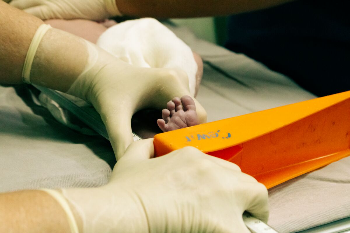 Newborn's foot being measured by a nurse in medical setting with care.