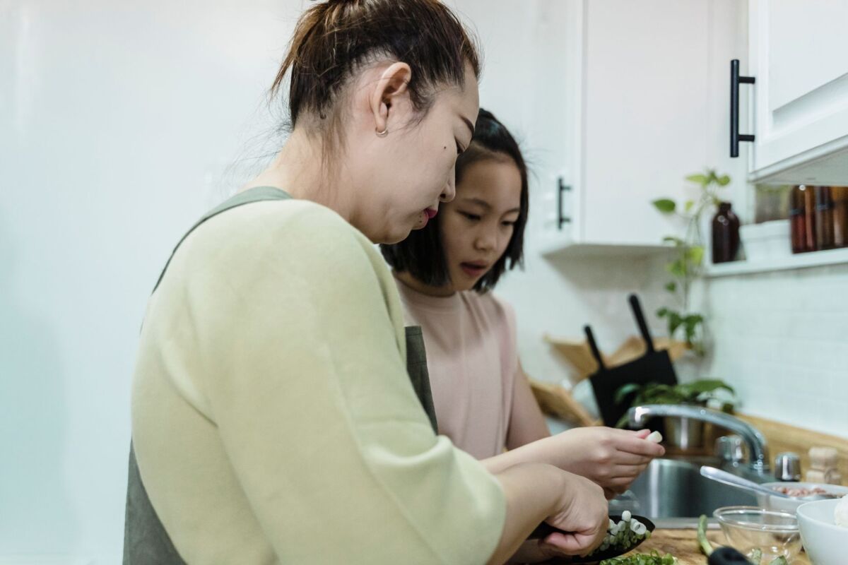 Mother and daughter enjoying quality time cooking together in a modern kitchen setting.