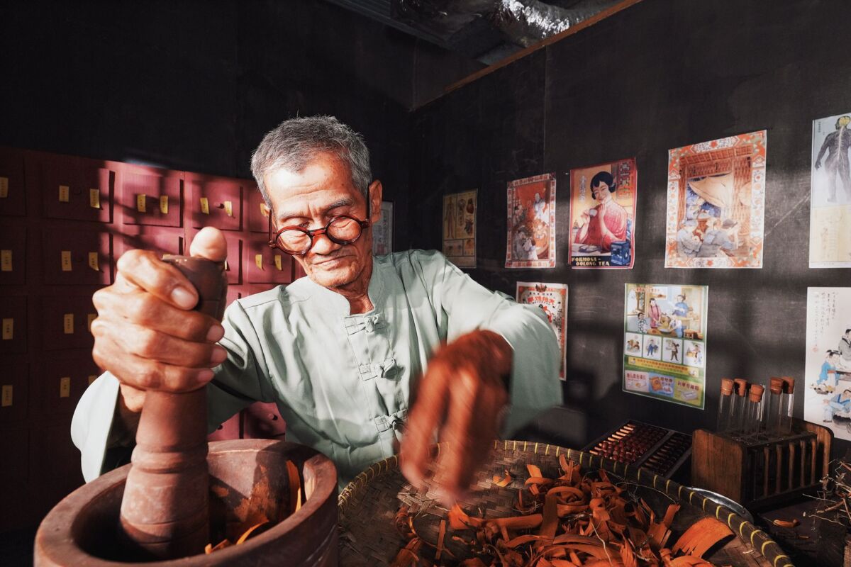 An elderly man in a traditional setting preparing herbs for Chinese medicine.