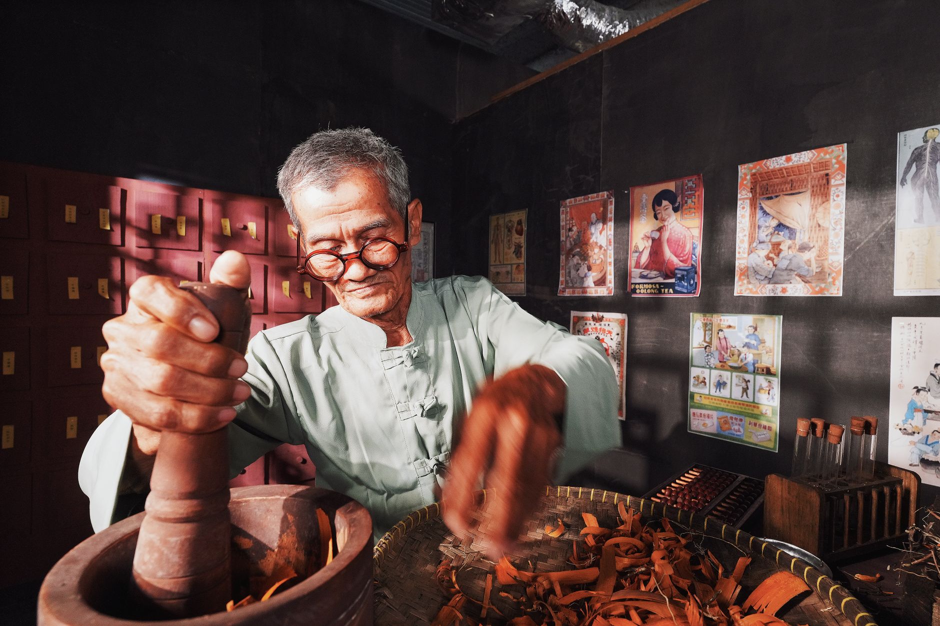 An elderly man in a traditional setting preparing herbs for Chinese medicine.