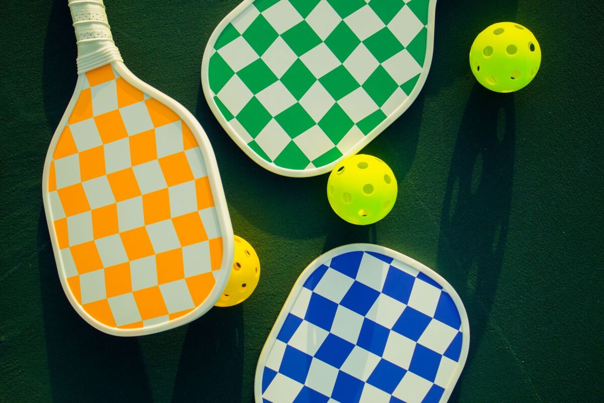Vibrant pickleball paddles and balls arranged on a sunny sports court.