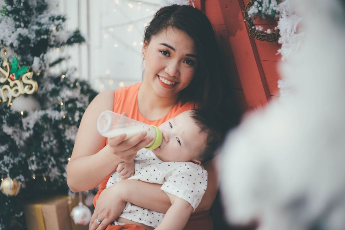 An Asian mother happily feeds her baby with a bottle during the Christmas holiday season.