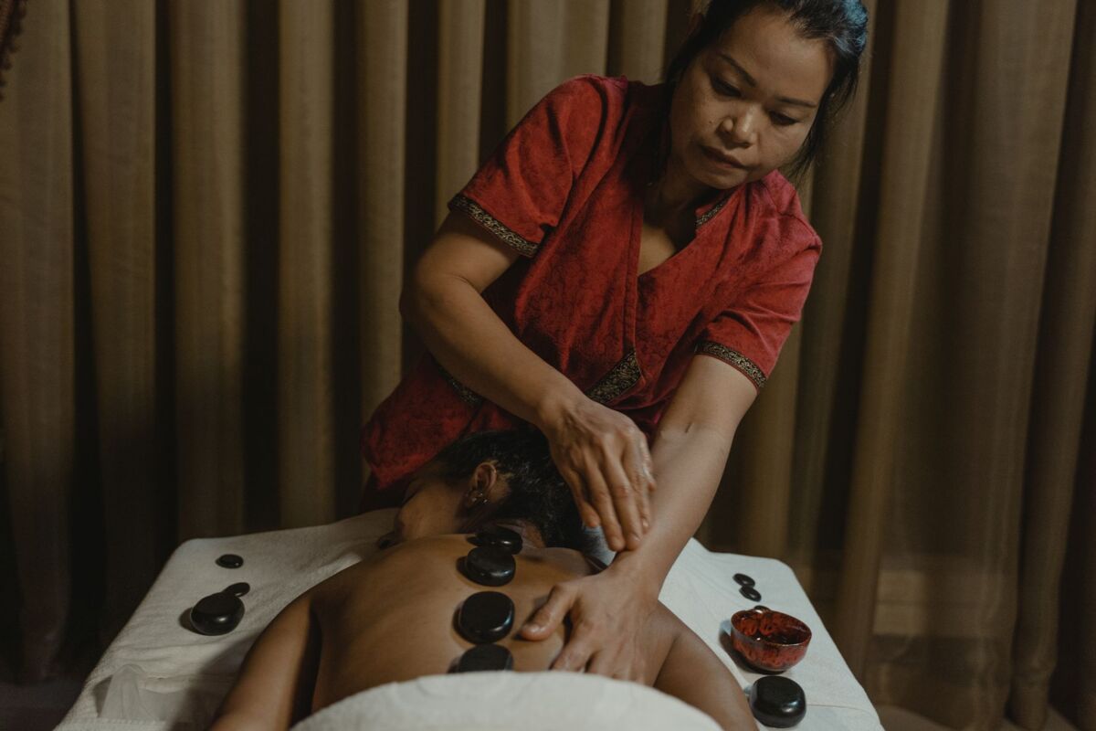 Skilled therapist giving a relaxing hot stone massage for wellness and relaxation indoors.