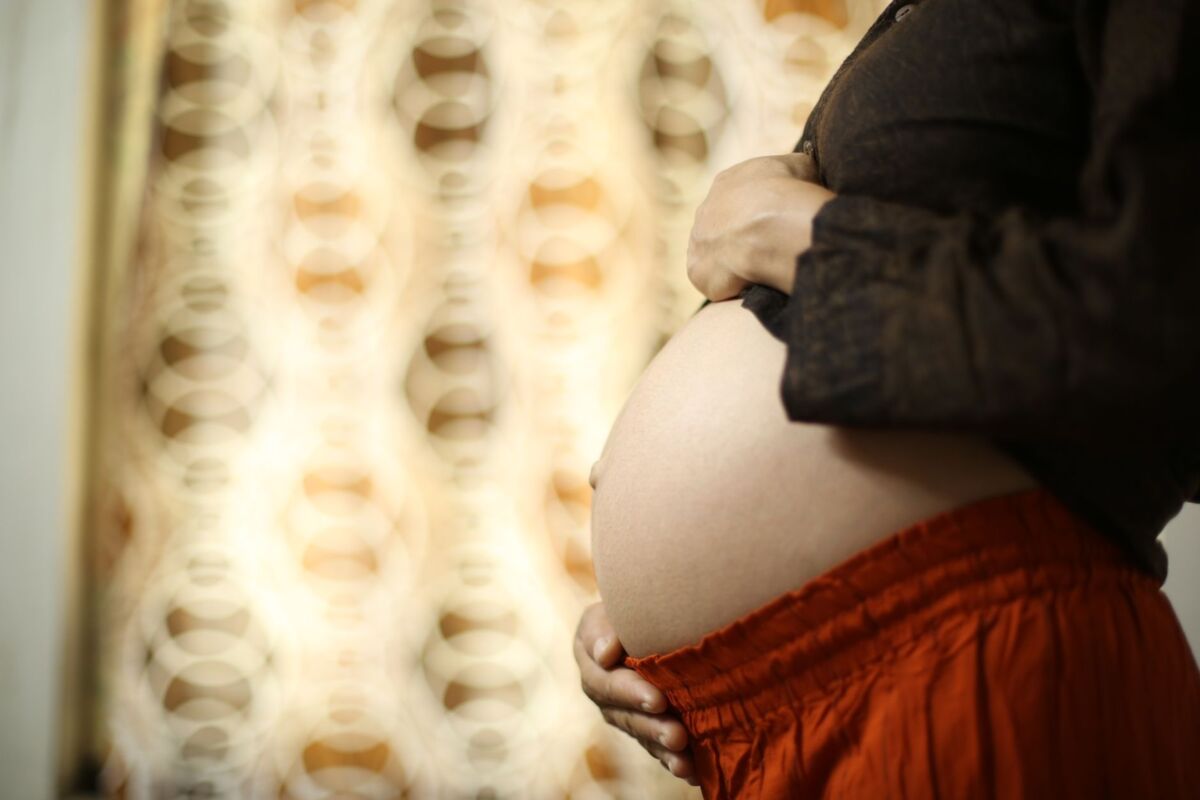 Intimate close-up of a pregnant woman's belly with hands touching, showcasing motherhood and love.
