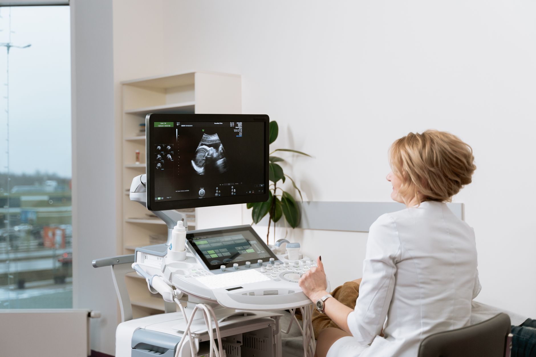 Doctor performing a prenatal ultrasound scan with medical equipment in a clinic.